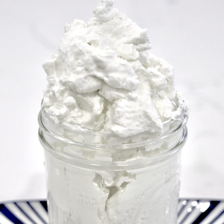 Homemade stabilized whipped cream in a jar on a decorative tray
