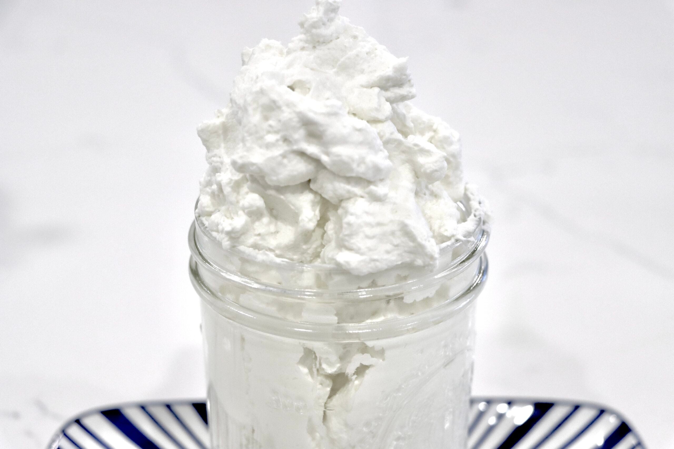 Homemade stabilized whipped cream in a jar on a decorative tray