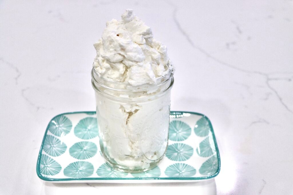 Homemade stabilized whipped cream in a jar on a decorative tray
