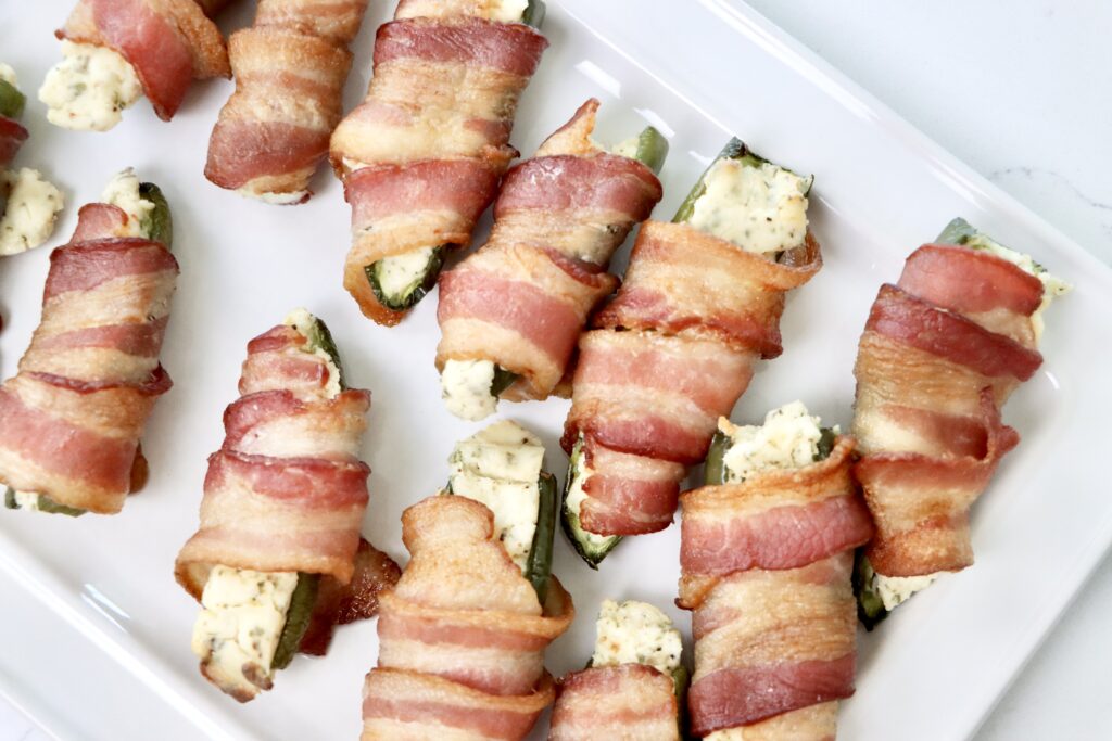 Bacon Wrapped jalepeno poppers on a white serving tray