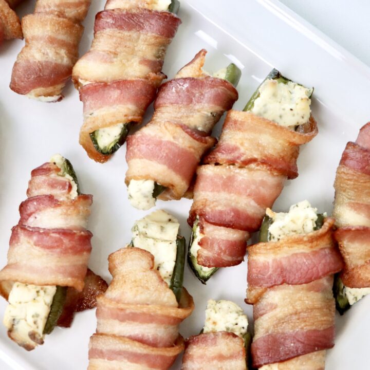 Bacon Wrapped jalepeno poppers on a white serving tray