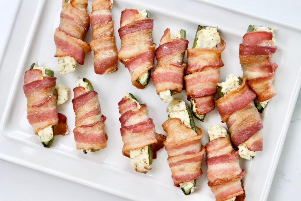 Bacon Wrapped jalepeno poppers on a white serving tray