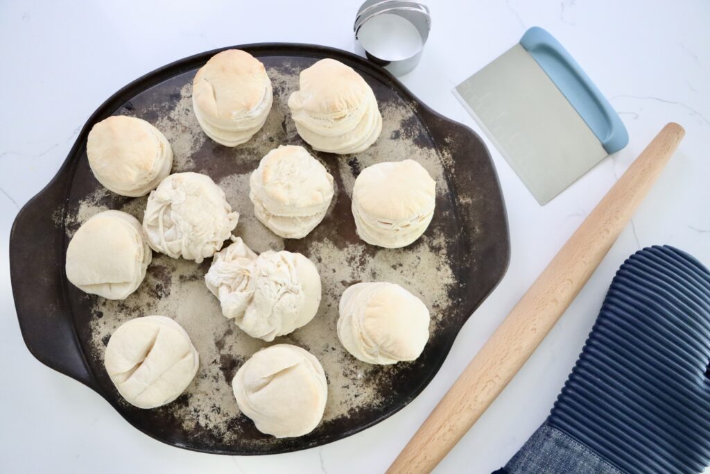 Sourdough Biscuits on a pan with a rolling pin, bench scraper and a biscuit cutter