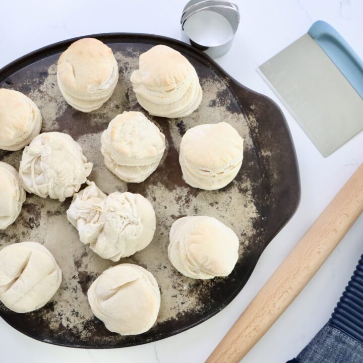 Sourdough Biscuits on a pan with a rolling pin, bench scraper and a biscuit cutter