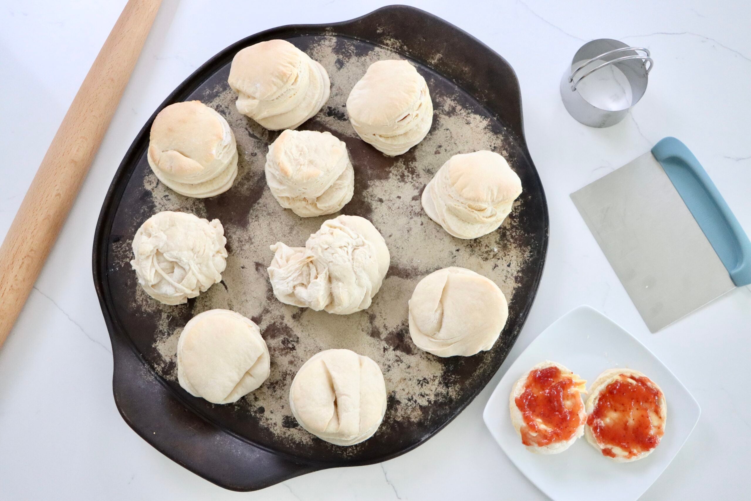 Sourdough Biscuits on a pan with a rolling pin, bench scraper and a biscuit cutter