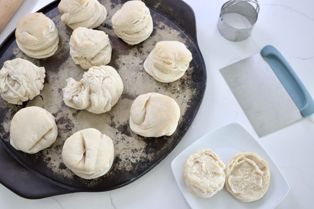Sourdough Biscuits on a pan with a rolling pin, bench scraper and a biscuit cutter