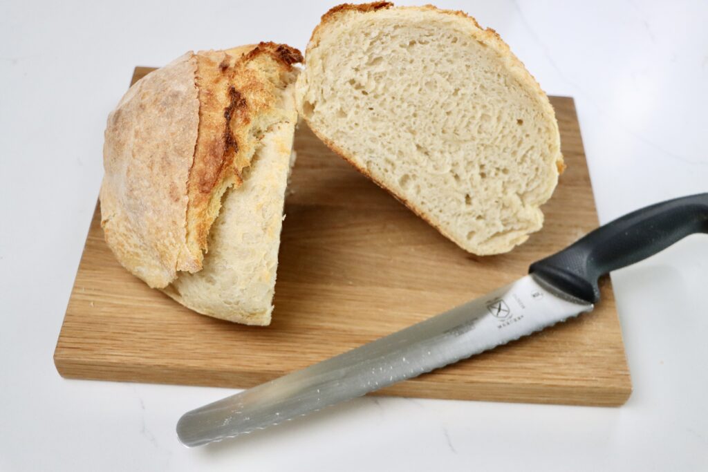 a loaf of sourdough bread cut in half on a cutting board with a knife