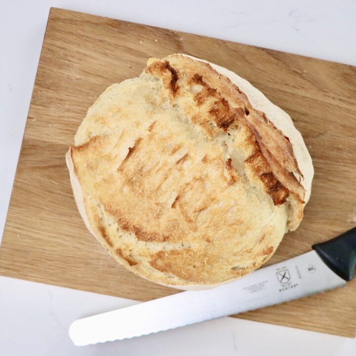 a loaf of sourdough bread on a cutting board with a knife