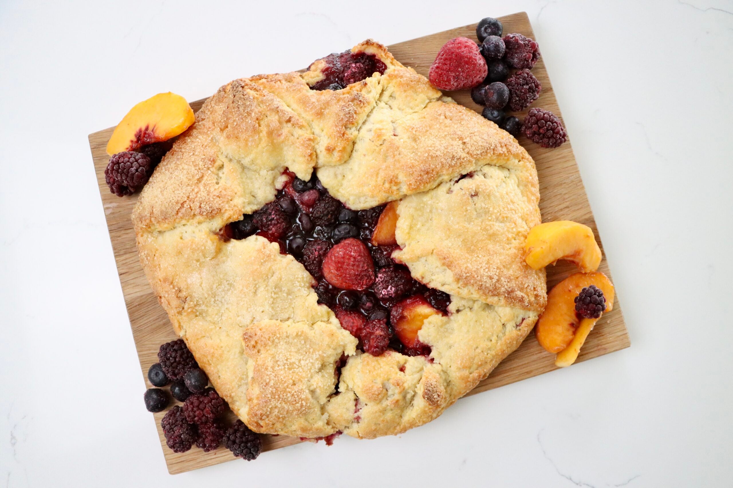 Rustic Berry Peach Galette on a cutting board with fruit