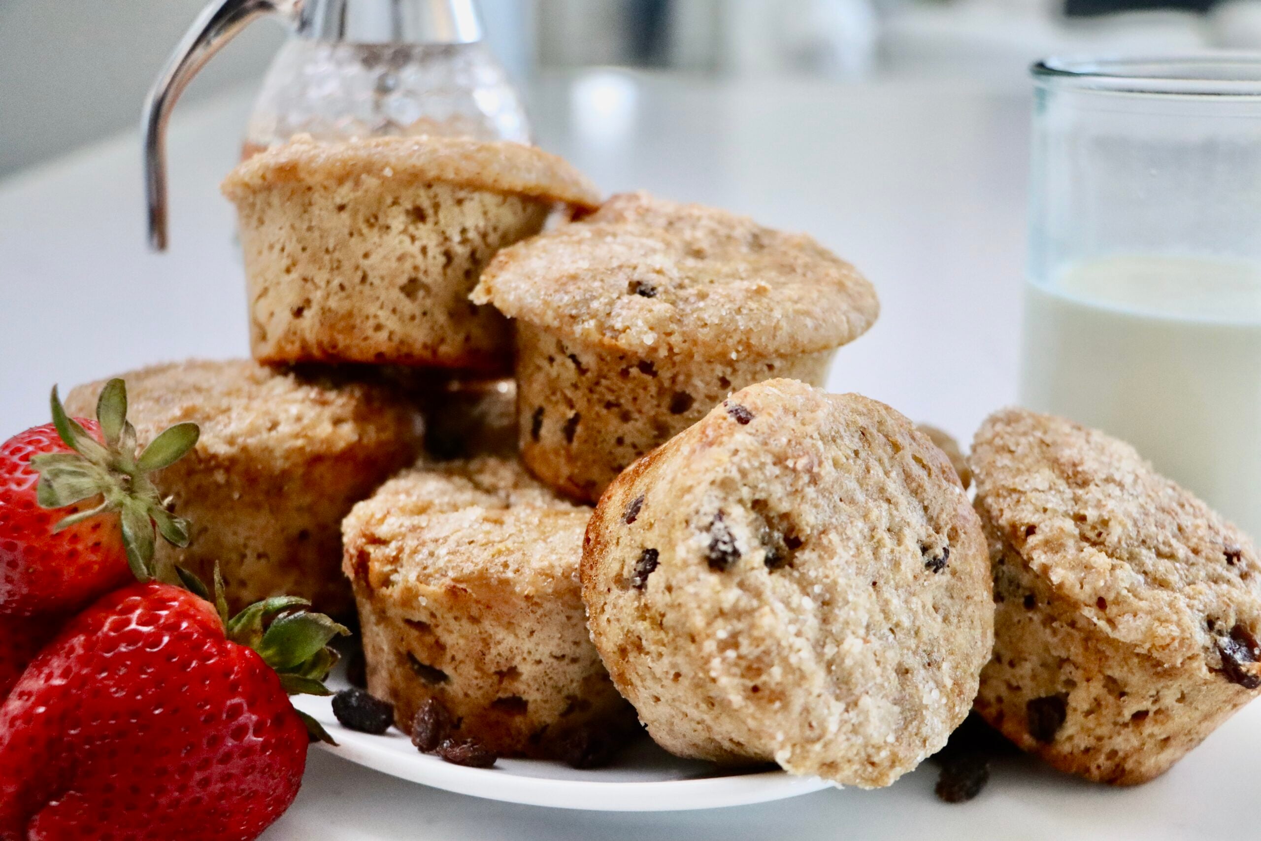Whole Wheat Yogurt Muffins on a plate with a glass of milk and a jar of honey