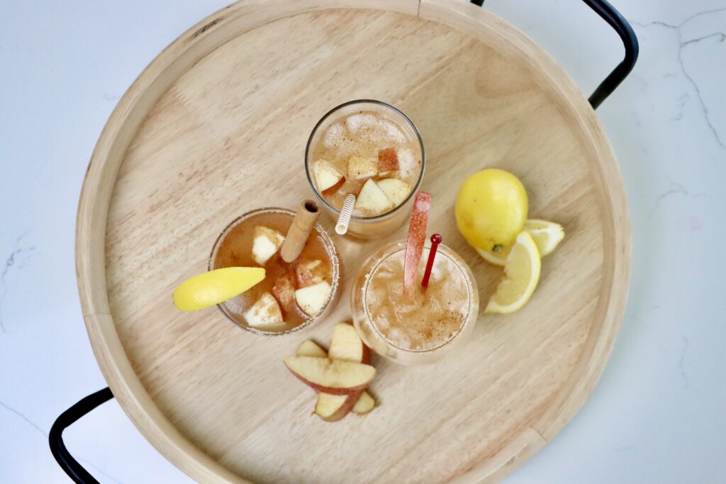 Three glasses of sparkling apple cider on a drink tray