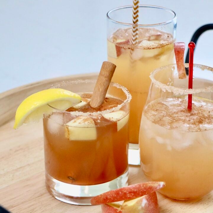 Three glasses of sparkling apple cider on a drink tray