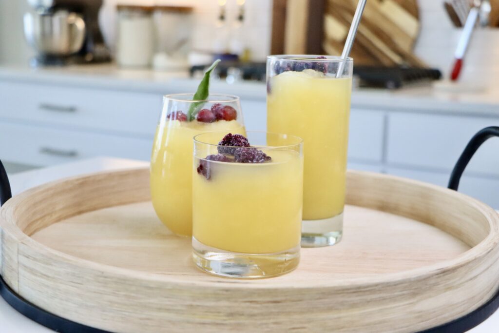 3 glasses of Golden Slushy Punch garnished with frozen fruit