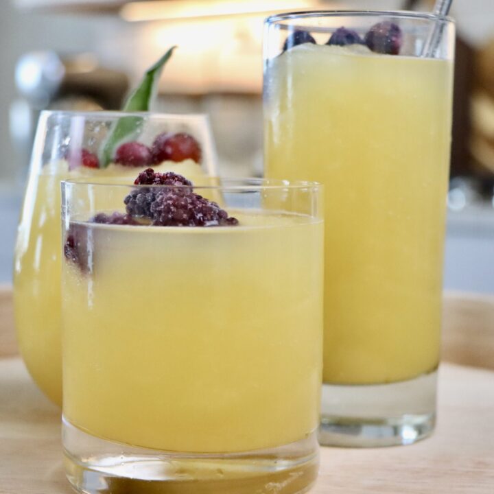 3 glasses of Golden Slushy Punch garnished with frozen fruit