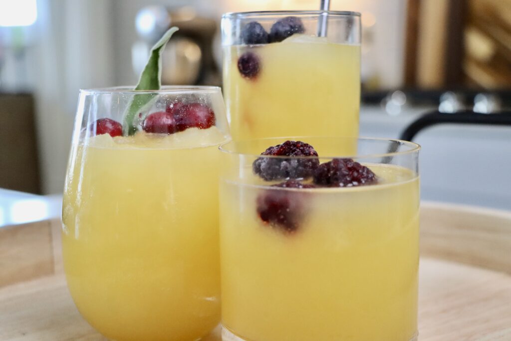 3 glasses of Golden Slushy Punch garnished with frozen fruit