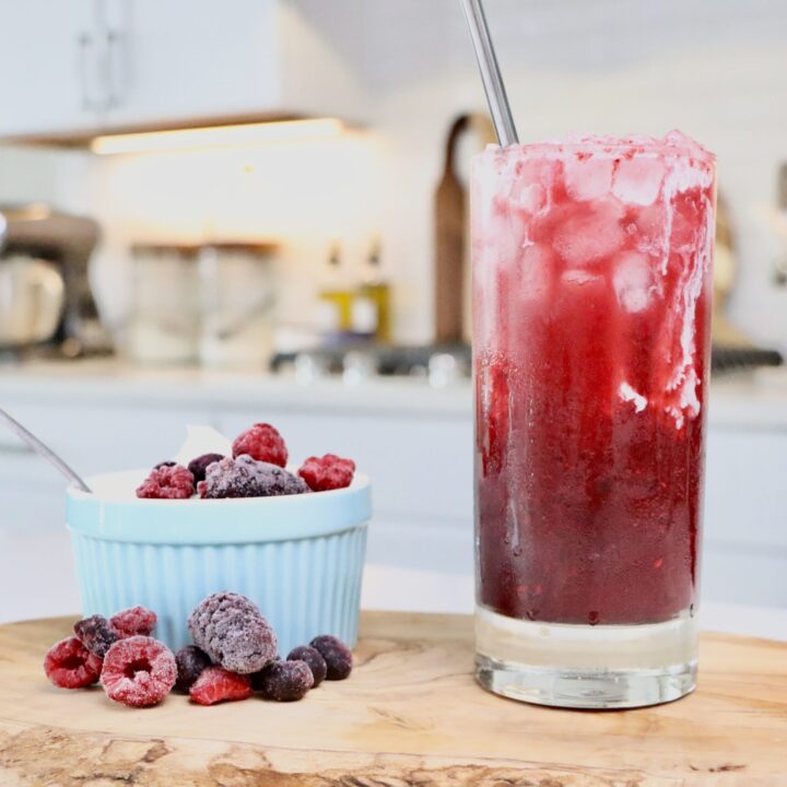 Homemade Cream Soda sitting on a cutting board next to a bowl of homemade whipped cream and berries