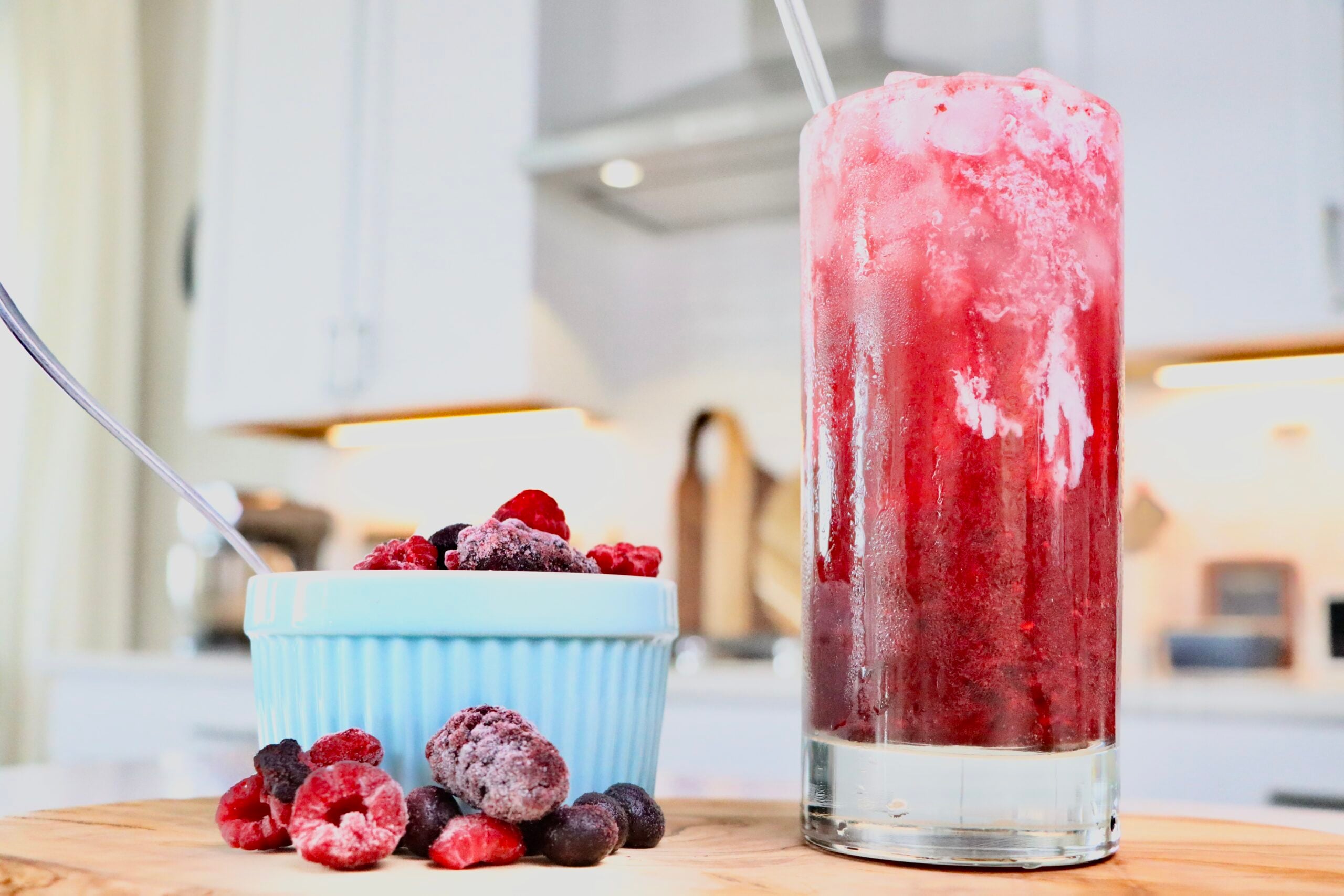 Homemade Cream Soda sitting on a cutting board next to a bowl of homemade whipped cream and berries