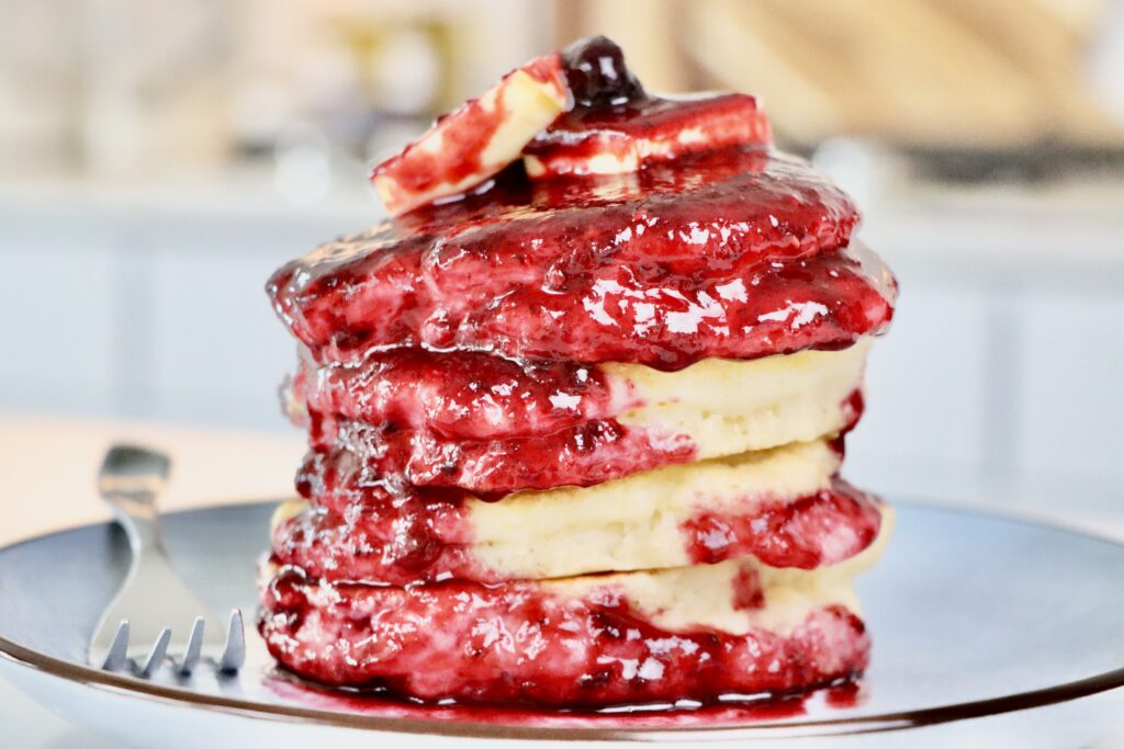 Homemade Sourdough Pancakes Smothered in Homemade Mixed Berry Sauce on a plate.