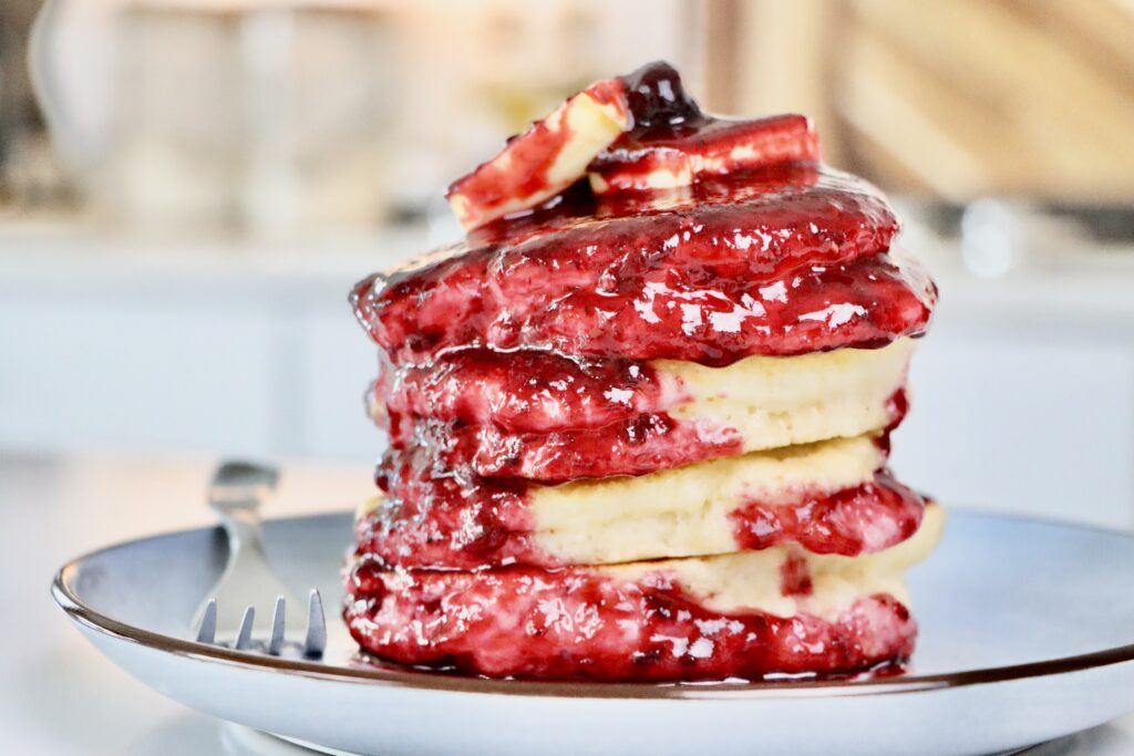 Homemade Sourdough Pancakes Smothered in Homemade Mixed Berry Sauce on a plate.