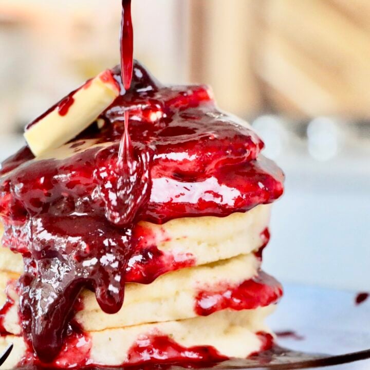 Homemade Sourdough Pancakes Smothered in Homemade Mixed Berry Sauce on a plate.