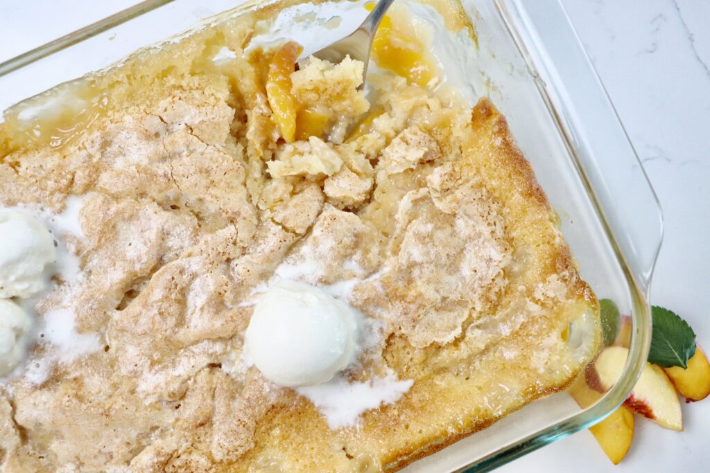 Homemade peach cobbler baked in a 9x13 pan with a golden brown topping and bubbling peach filling
