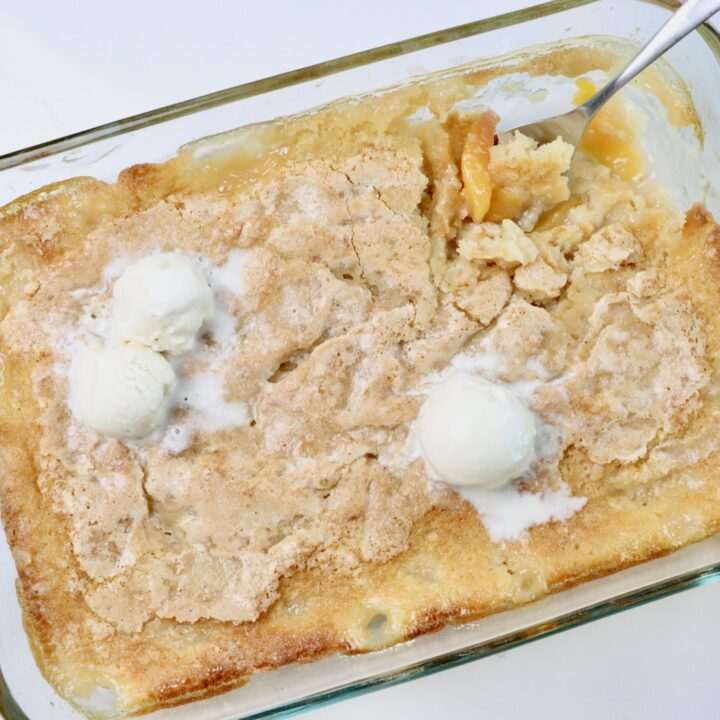 Homemade peach cobbler baked in a 9x13 pan with a golden brown topping and bubbling peach filling