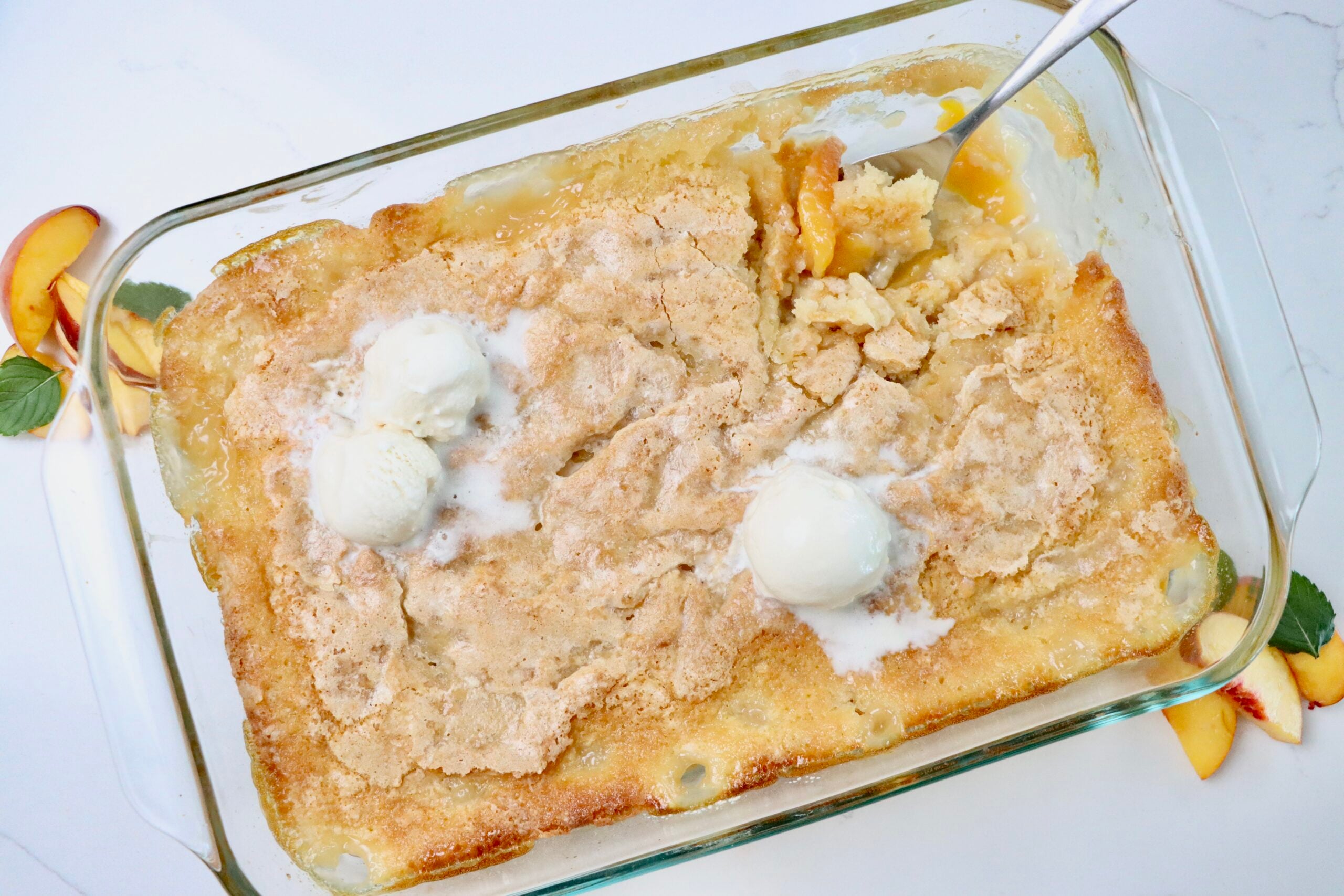 Homemade peach cobbler baked in a 9x13 pan with a golden brown topping and bubbling peach filling