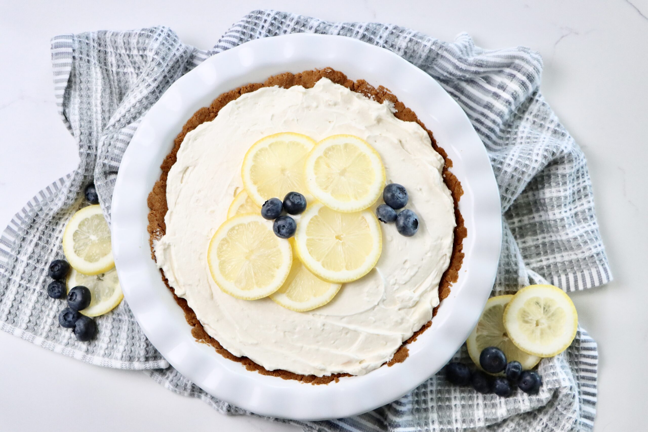 Homemade Lemon Pie topped with homemade stabilized whipped cream, lemon slices and fresh blueberries