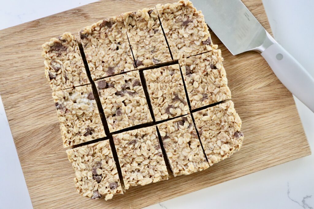 Overhead shot of chewy peanut butter marshmallow chocolate chip granola bars cut into squares on a cutting board