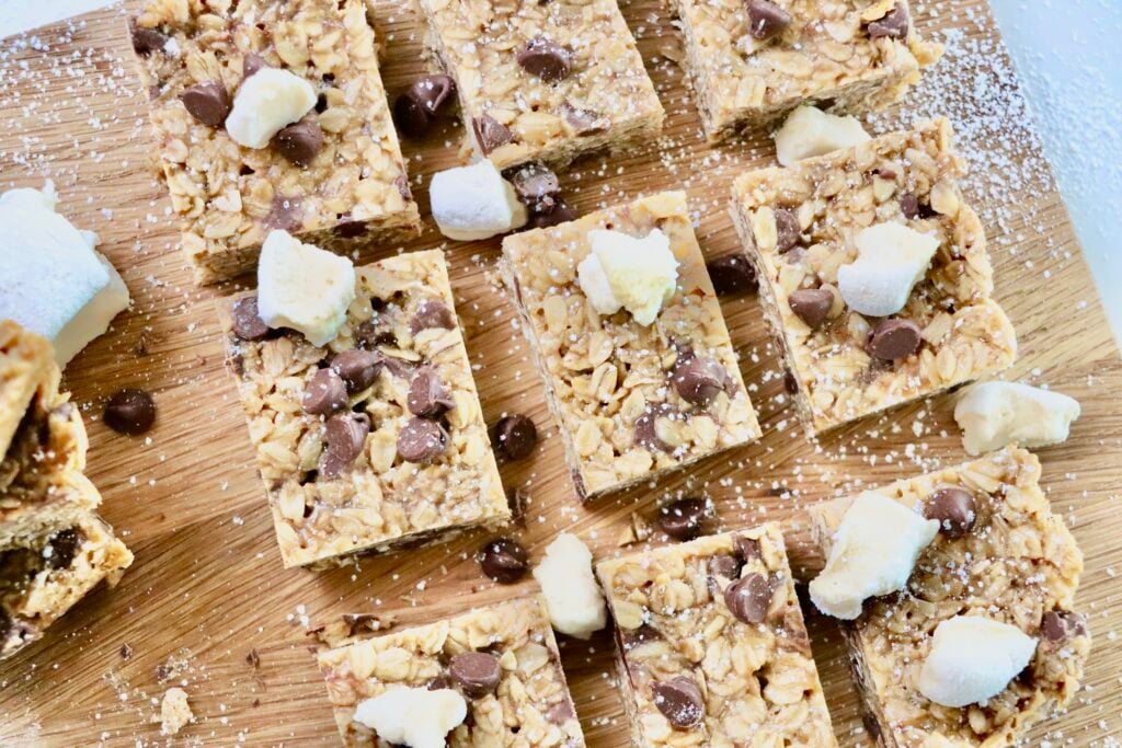 Overhead shot of chewy peanut butter marshmallow chocolate chip granola bars cut into squares on a cutting board