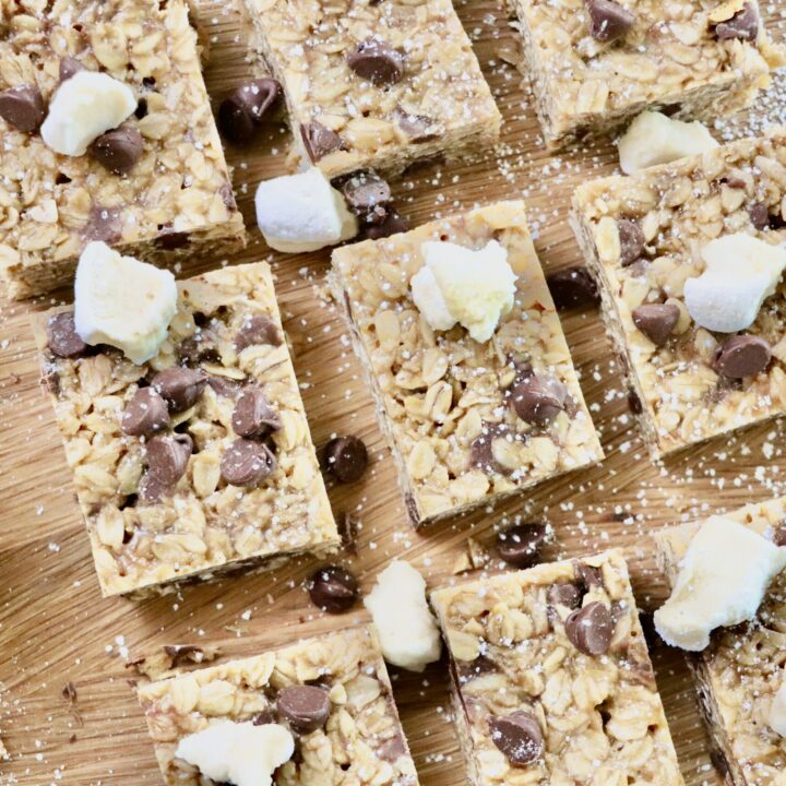 Overhead shot of chewy peanut butter marshmallow chocolate chip granola bars cut into squares on a cutting board