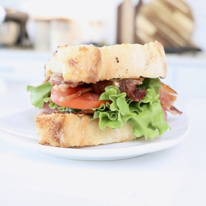 BLT Sandwich on homemade sourdough bread with homemade herb mayo sitting on a white plate