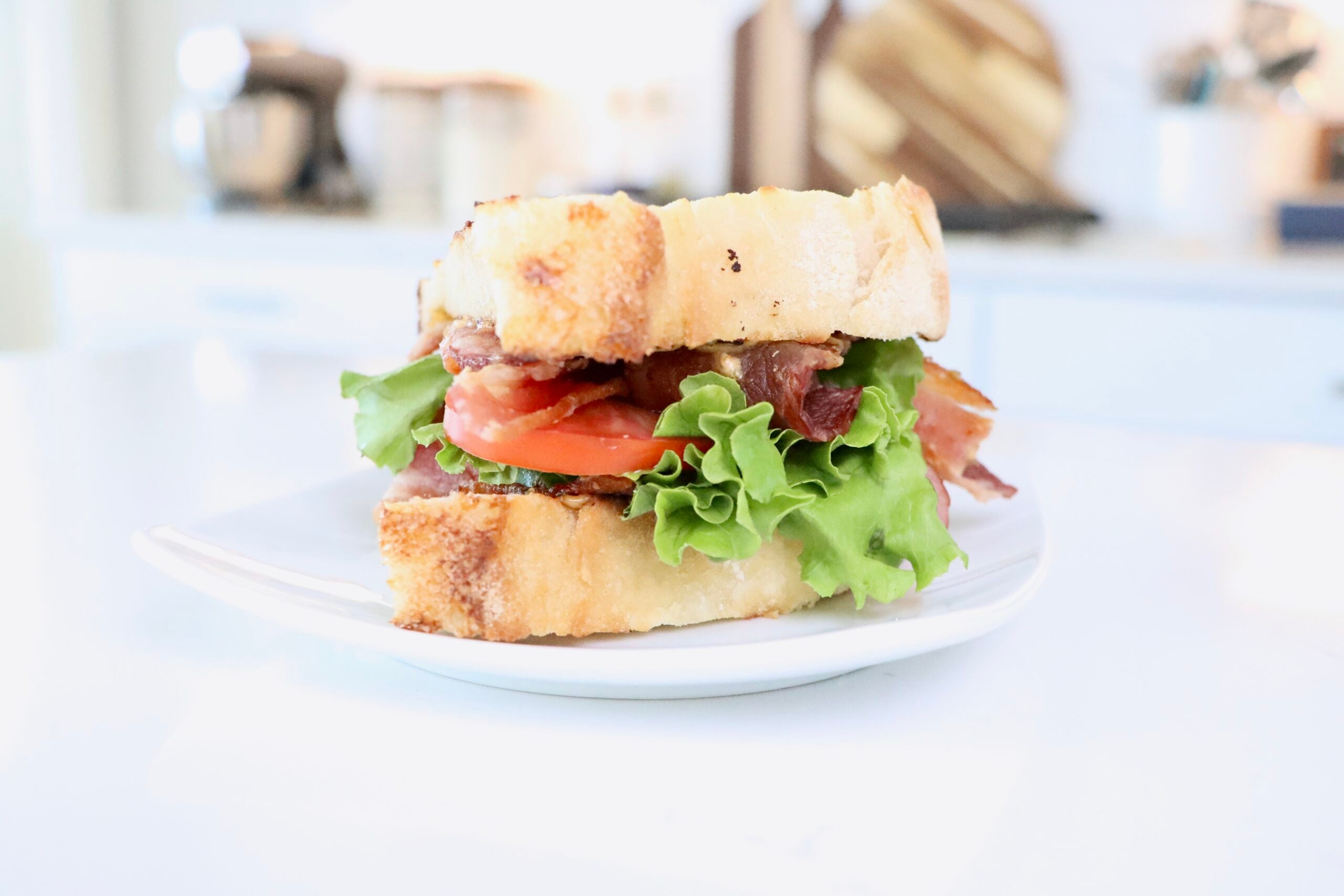 BLT Sandwich on homemade sourdough bread with homemade herb mayo sitting on a white plate