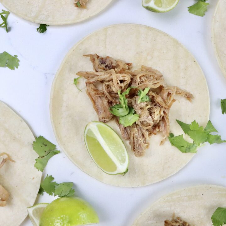 Citrusy carnitas served in soft corn tortillas with fresh cilantro and lime wedges, juicy pork shoulder shredded and topped with orange and lime zest.