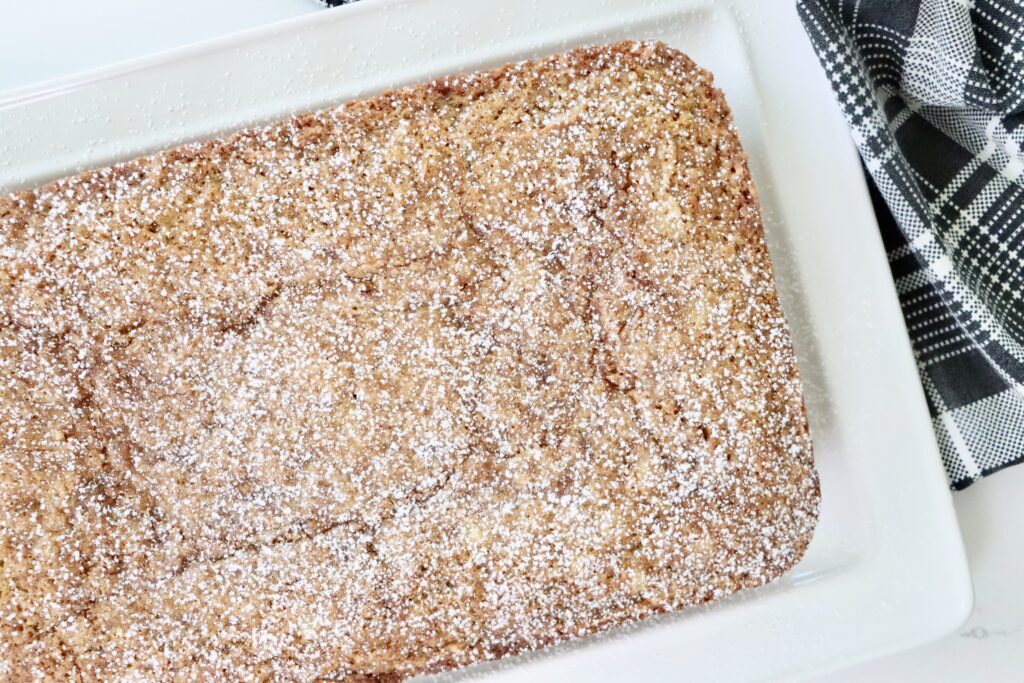 Freshly baked zucchini cake with pineapple on a plate, topped with a light dusting of powdered sugar.