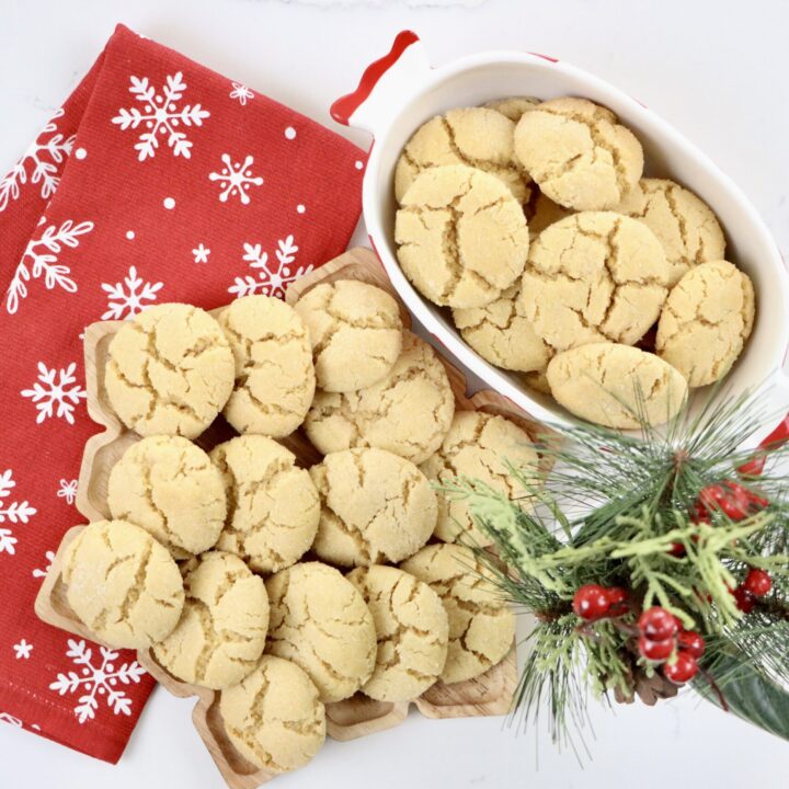 Soft, buttery Angel Cookies on a snowflake tray and bowl with golden edges and sparkling sugar coating