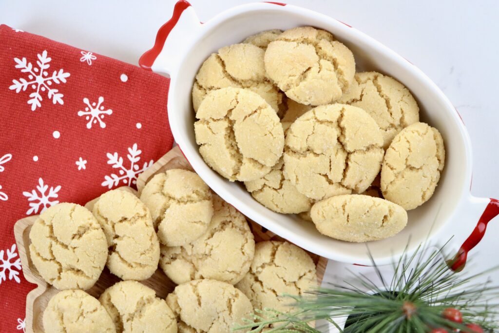 Soft, buttery Angel Cookies on a snowflake tray and bowl with golden edges and sparkling sugar coating