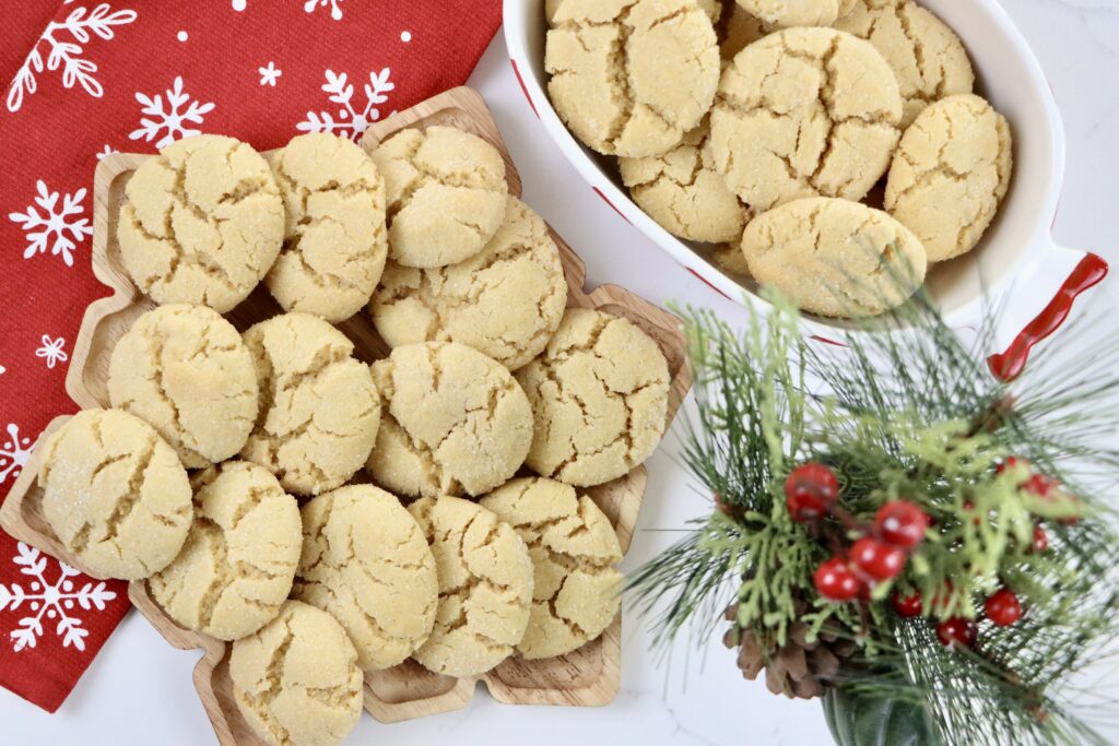 Soft, buttery Angel Cookies on a snowflake tray and bowl with golden edges and sparkling sugar coating
