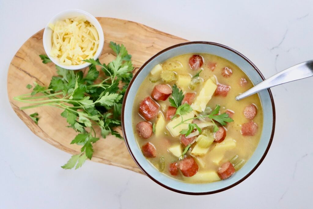Bowl of creamy hotdog potato soup with golden potatoes, sliced hotdogs, and fresh parsley on top