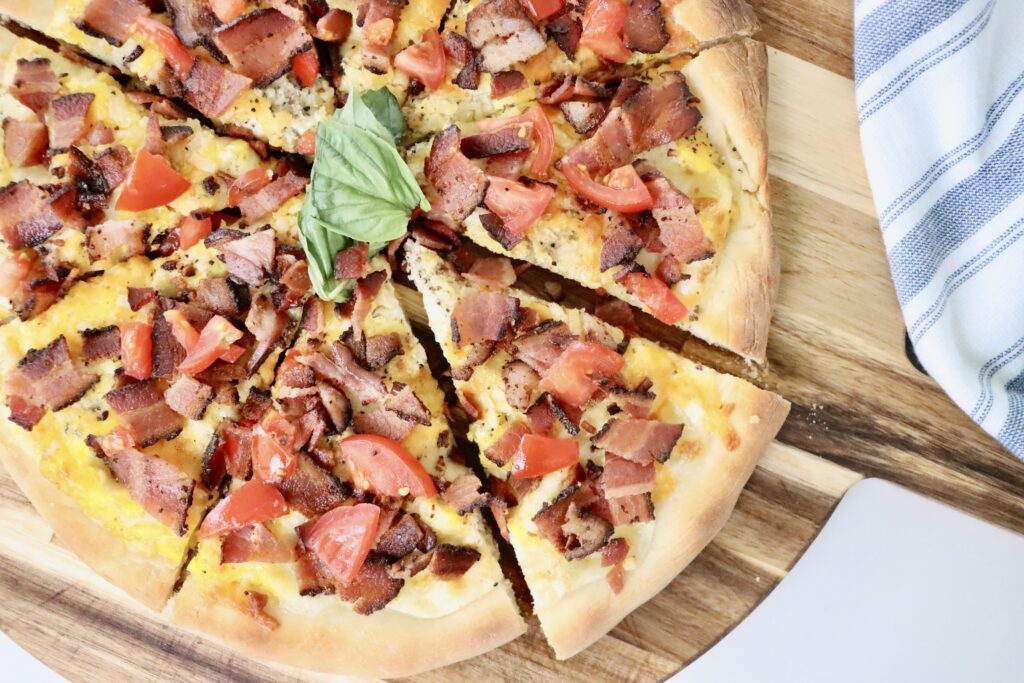 Homemade breakfast pizza baked on sourdough crust with eggs, crispy bacon, and melted cheese