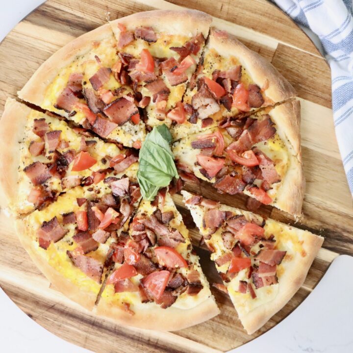 Homemade breakfast pizza baked on sourdough crust with eggs, crispy bacon, and melted cheese