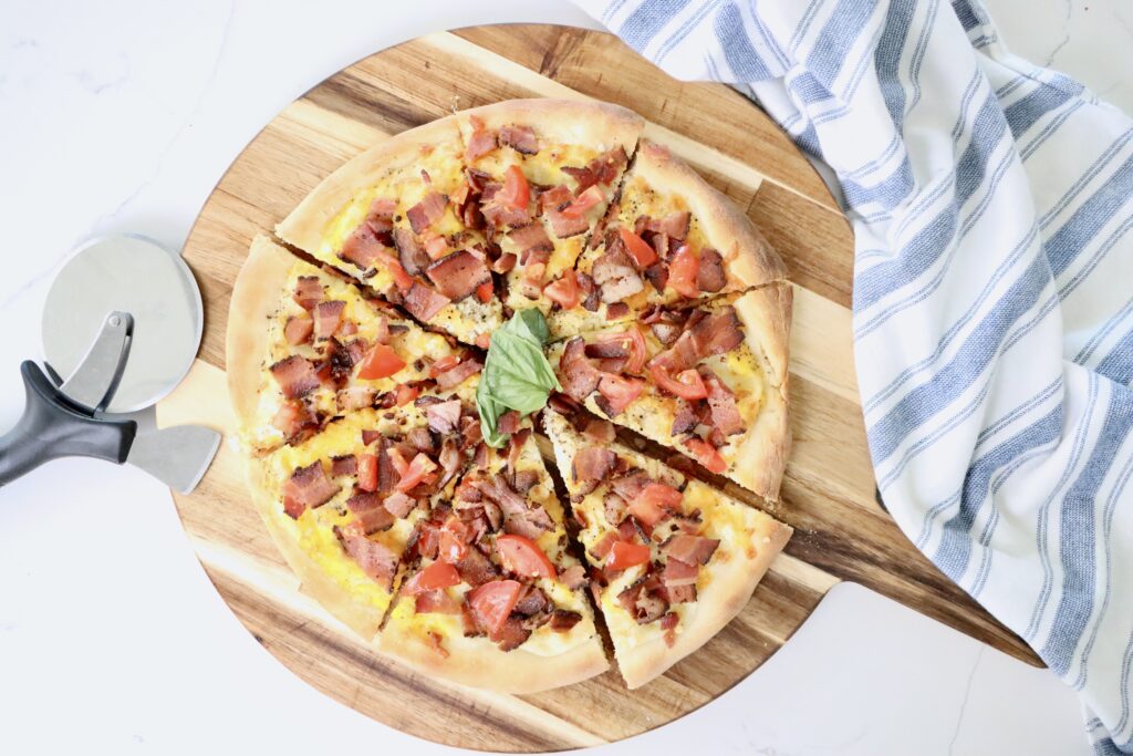 Homemade breakfast pizza baked on sourdough crust with eggs, crispy bacon, and melted cheese