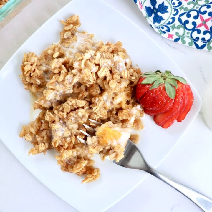 Baked oatmeal with fresh peaches in a 9x13 pan and a white plate, golden and fluffy, drizzled with cream, ready to serve for breakfast