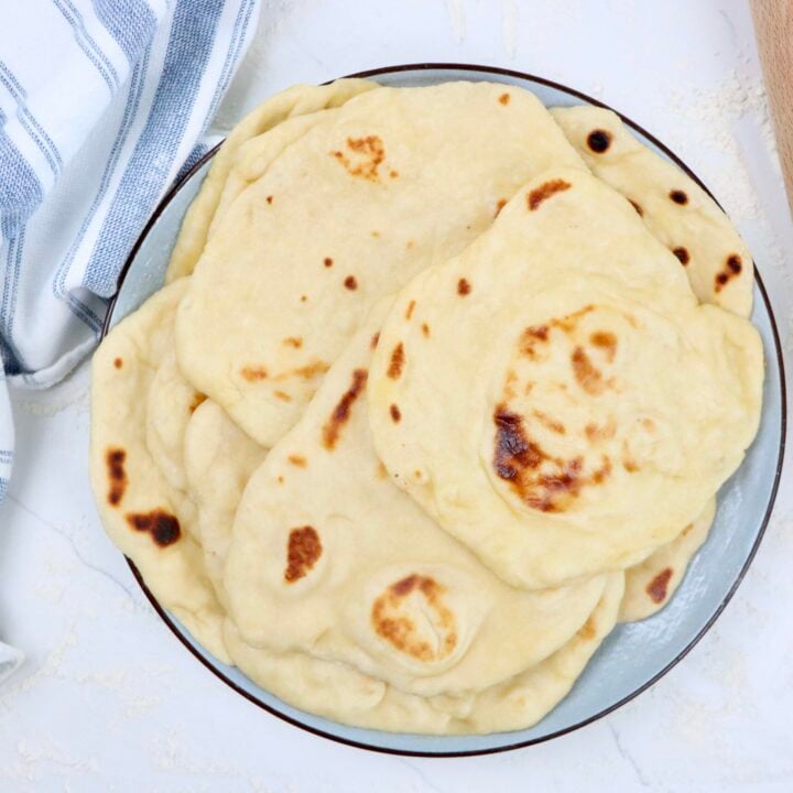 Stack of soft and chewy sourdough naan bread brushed with melted butter