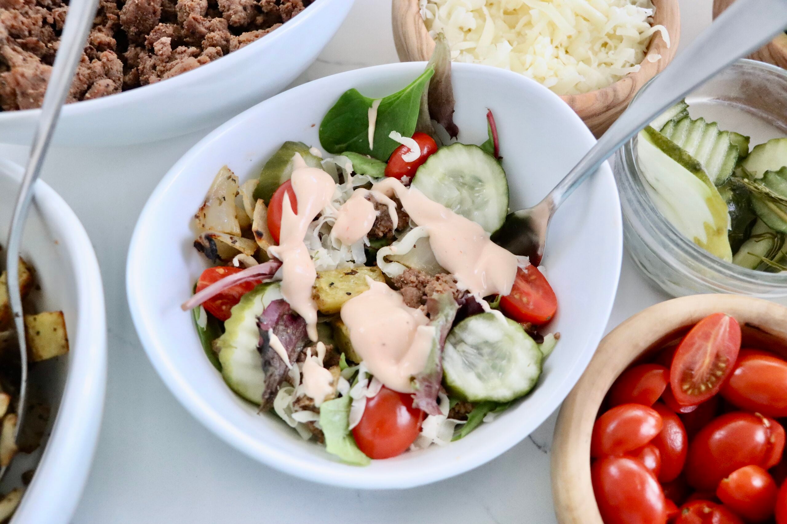 Burger bowl topped with homemade fry sauce, pickles, and roasted potatoes