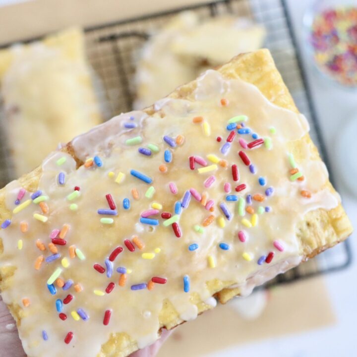 Flaky homemade pop tarts on cooling rack, filled with berry jam, drizzled with glaze, made from scratch with real ingredients.