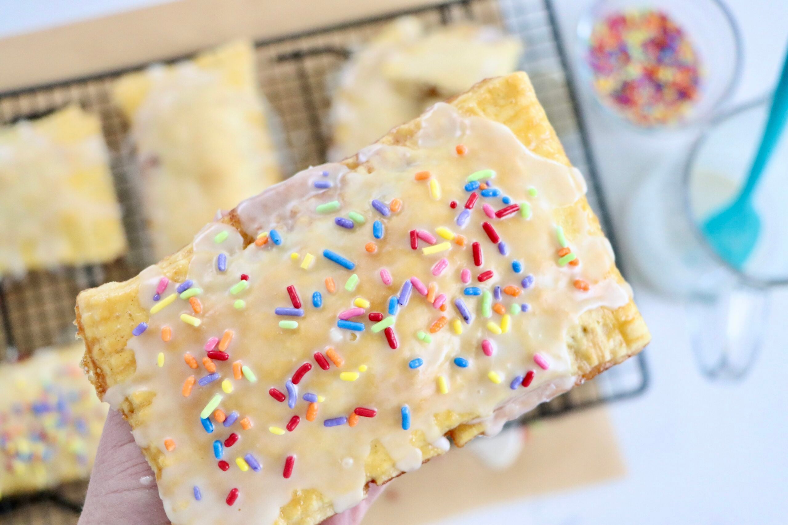 Flaky homemade pop tarts on cooling rack, filled with berry jam, drizzled with glaze, made from scratch with real ingredients.