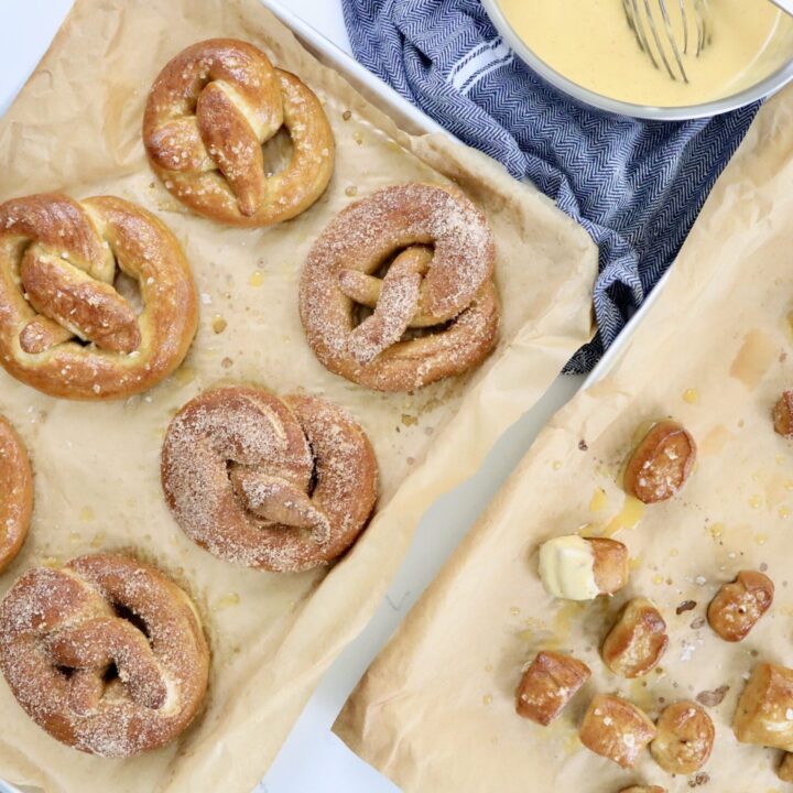 Soft, golden brown sourdough pretzels fresh out of the oven, sprinkled with Maldon salt on a parchment-lined baking sheet, homemade from scratch.