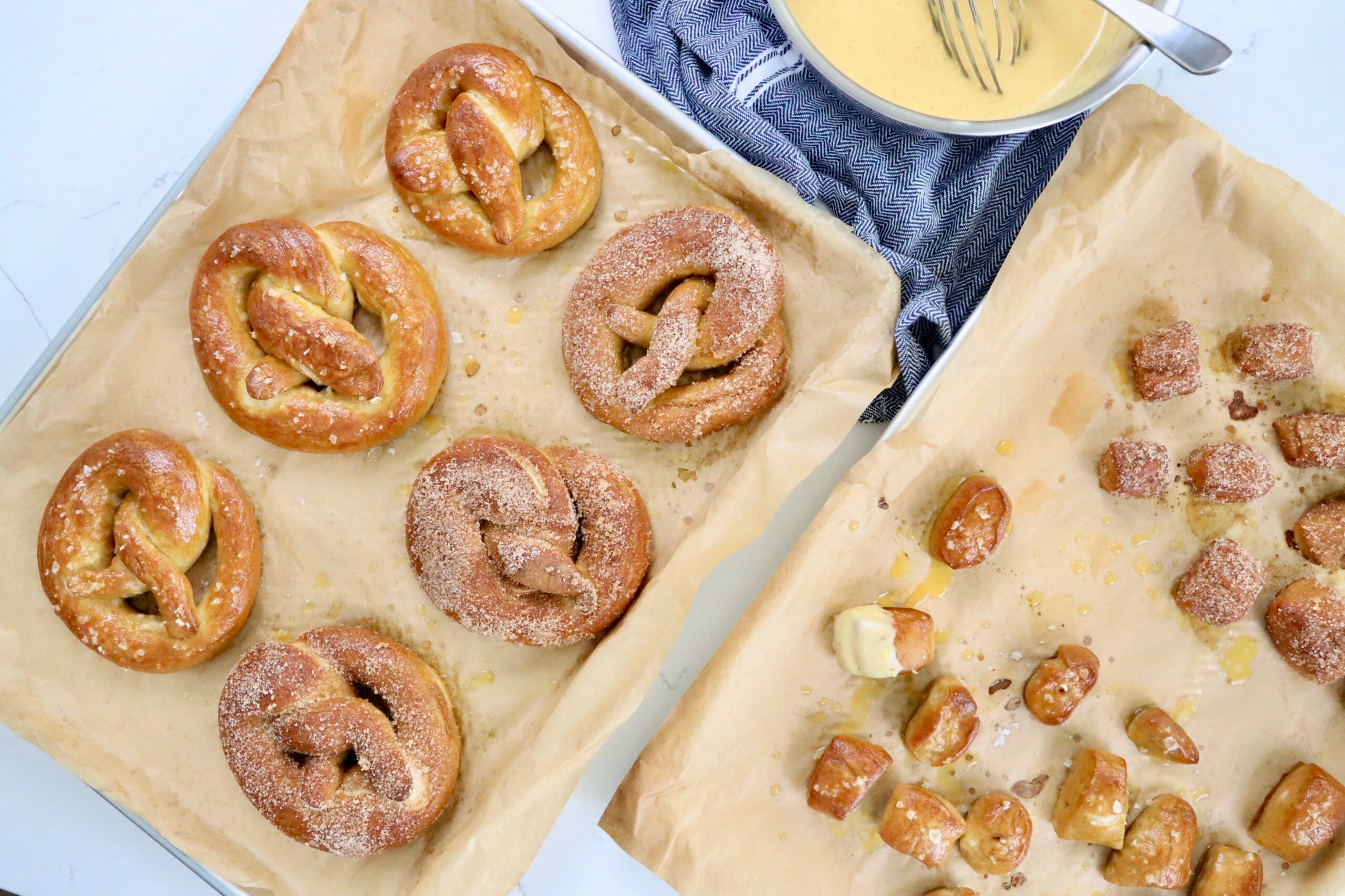 Soft, golden brown sourdough pretzels fresh out of the oven, sprinkled with Maldon salt on a parchment-lined baking sheet, homemade from scratch.