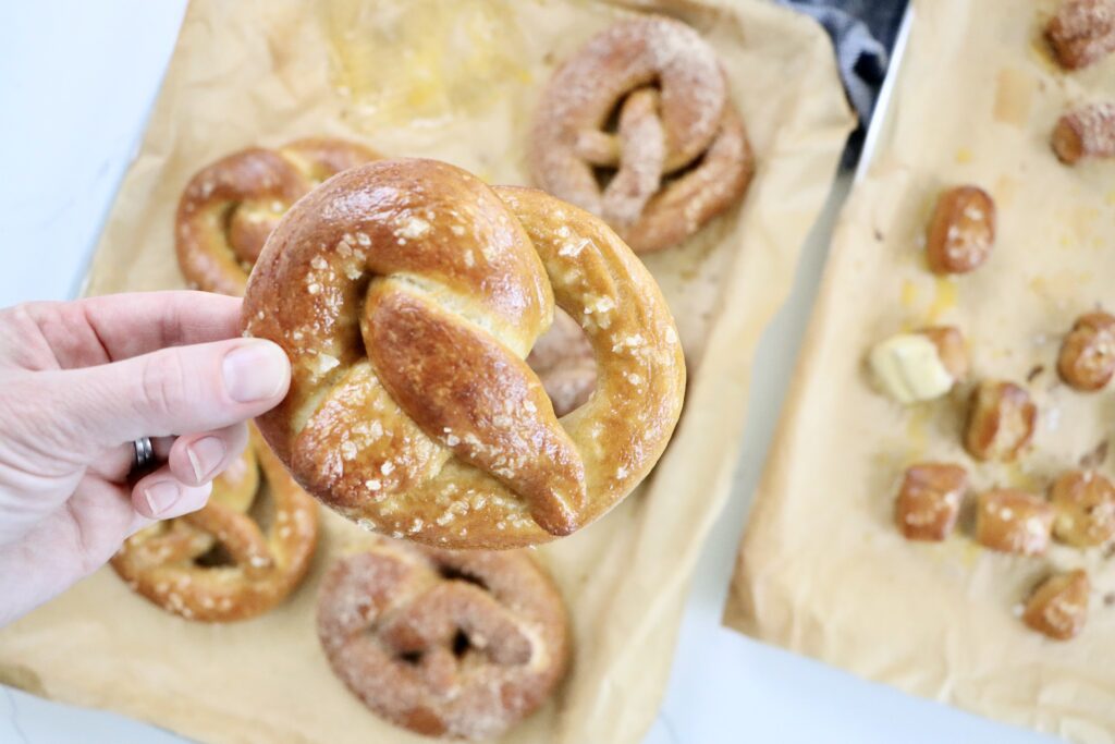 Soft, golden brown sourdough pretzels fresh out of the oven, sprinkled with Maldon salt on a parchment-lined baking sheet, homemade from scratch.